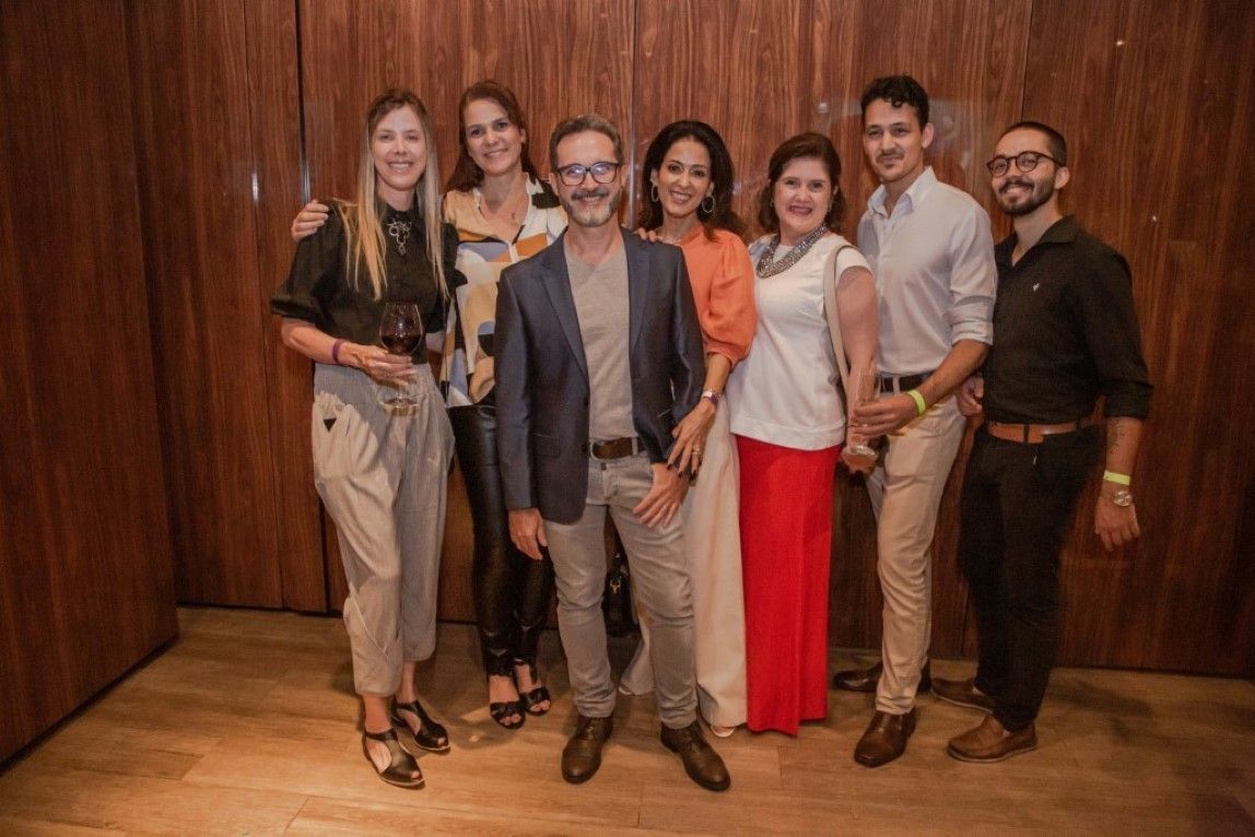 Um grupo de pessoas está posando para uma foto em frente a uma parede de madeira.