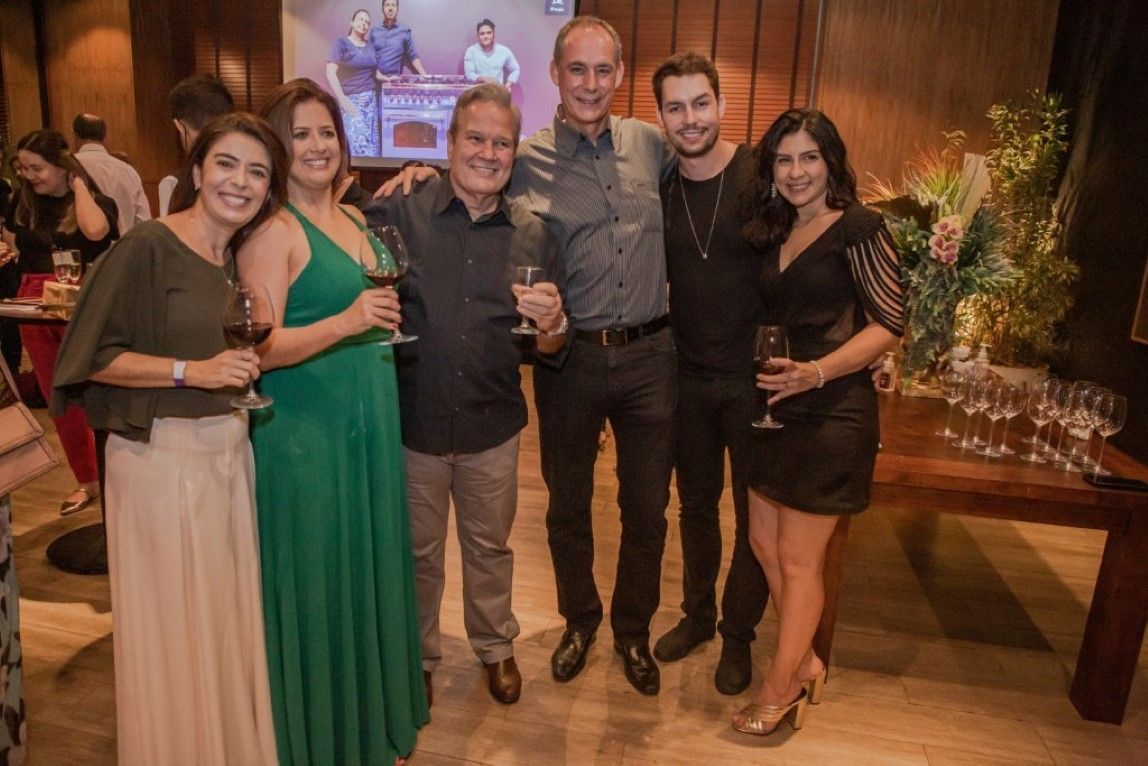 Um grupo de pessoas está posando para uma foto segurando taças de vinho.