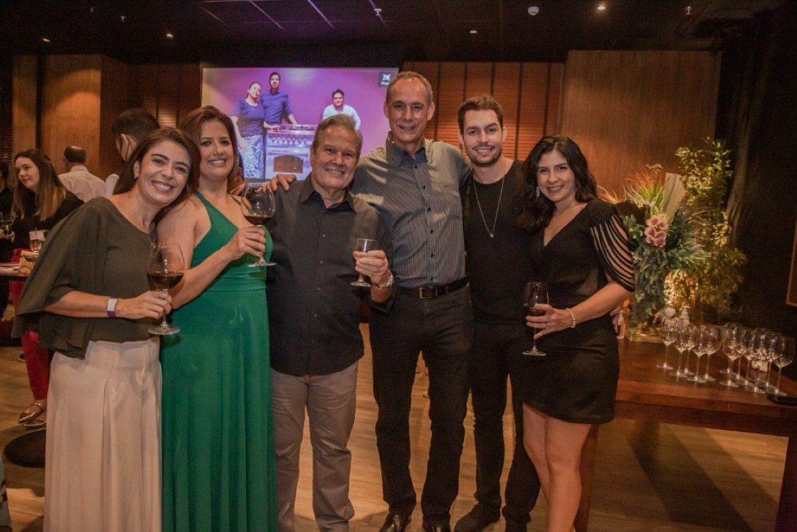 Um grupo de pessoas está posando para uma foto em uma sala enquanto seguram taças de vinho.