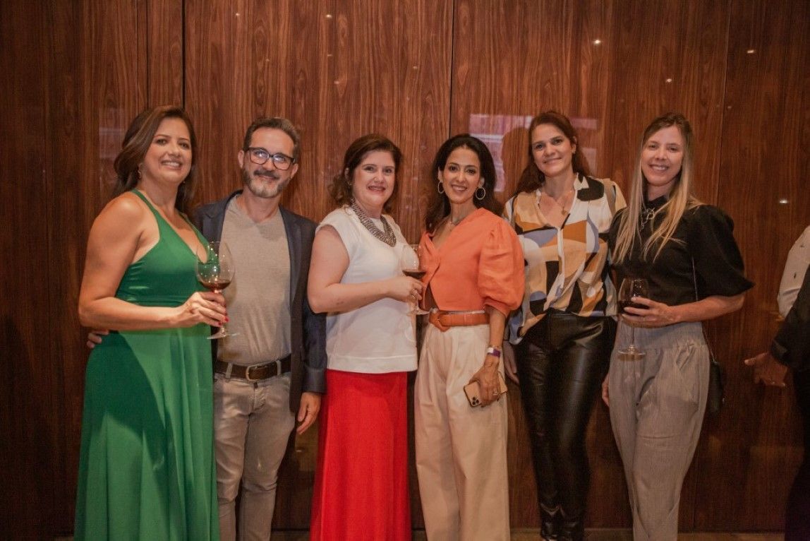 Um grupo de pessoas está posando para uma foto em frente a uma parede de madeira.
