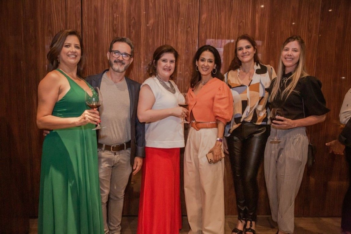 Um grupo de pessoas está posando para uma foto em frente a uma parede de madeira.