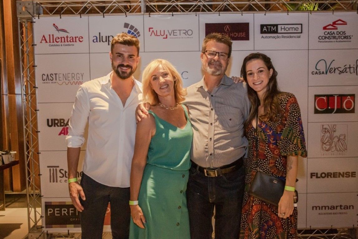 Um grupo de pessoas posando para uma foto em frente a uma parede com logotipos.