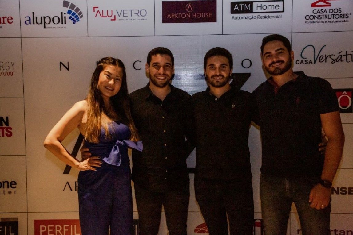 Um grupo de pessoas posando para uma foto em frente a uma parede que diz alupoli