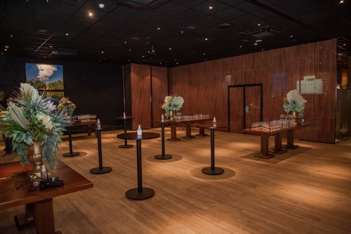 Uma sala grande com mesas de madeira e mesas com flores.
