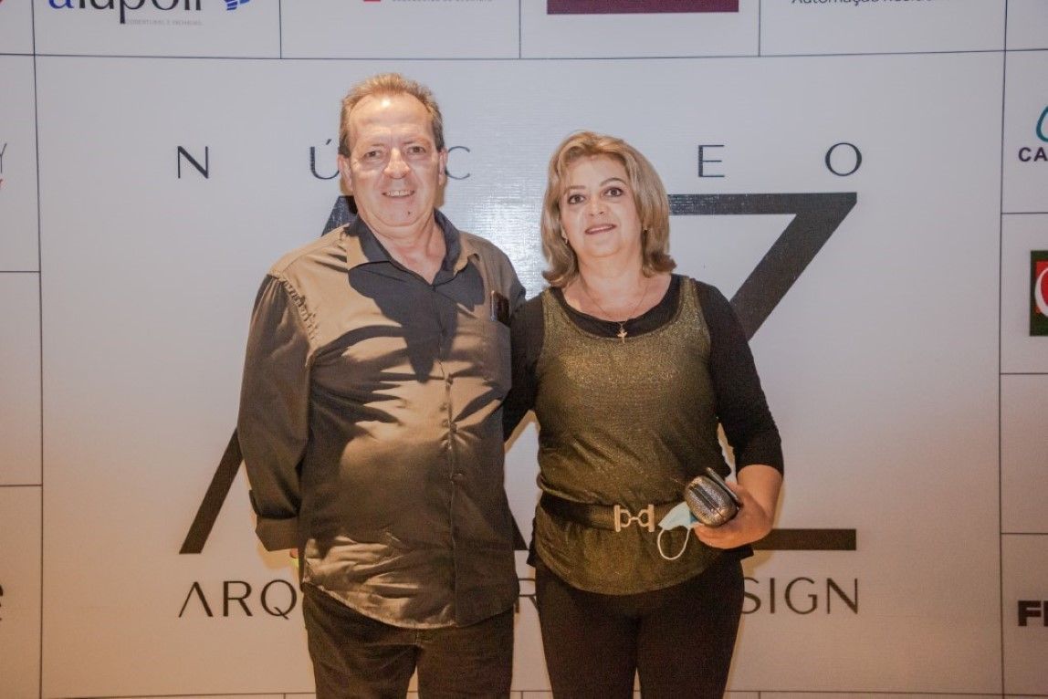 Um homem e uma mulher estão posando para uma foto em frente a uma placa que diz arco design