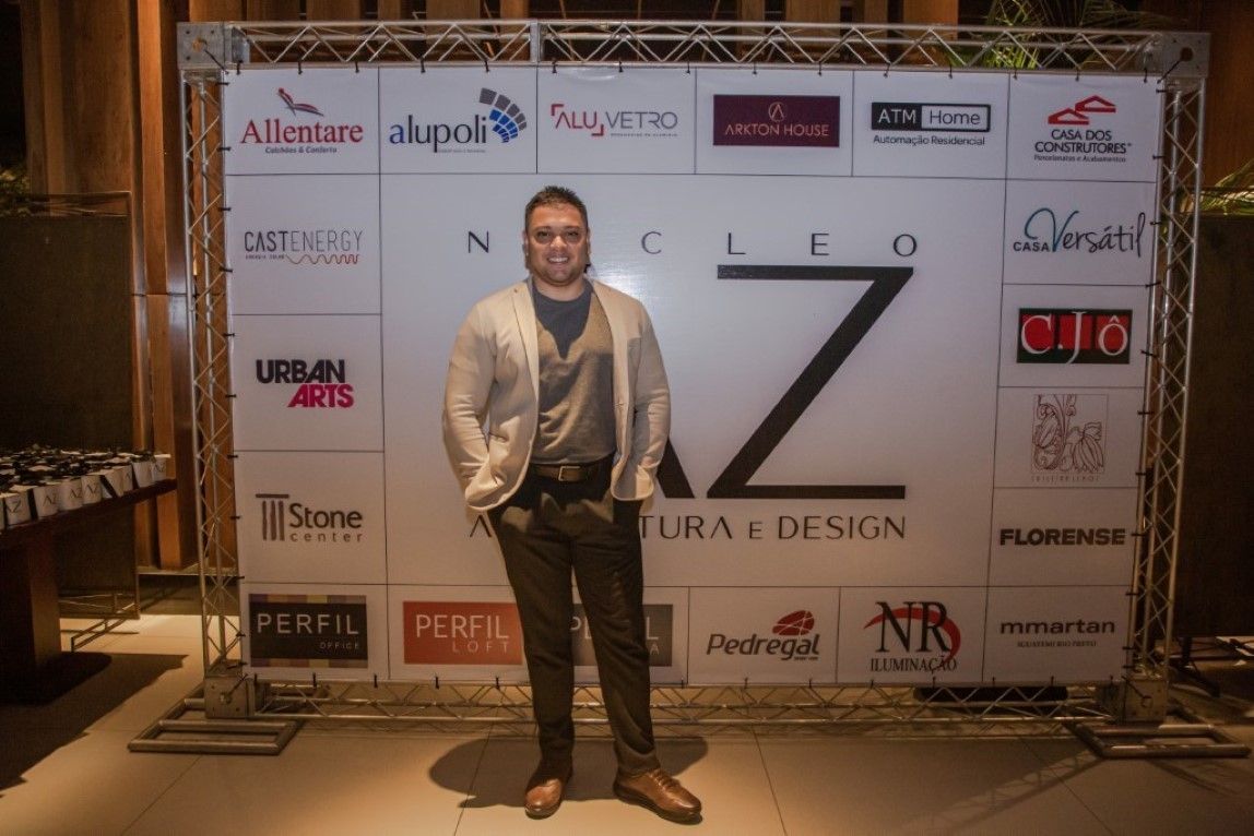Um homem está parado em frente a uma parede com logotipos nela.