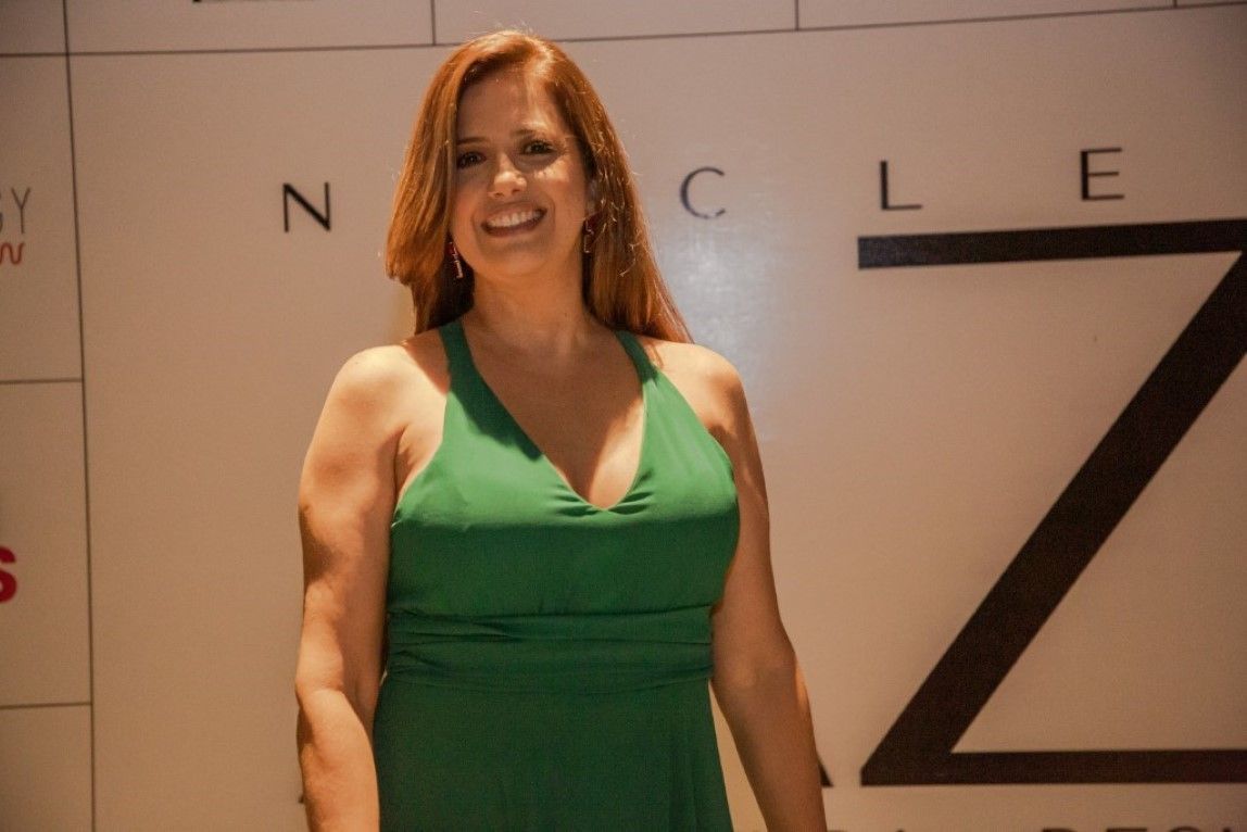 Uma mulher com um vestido verde está parada em frente a uma parede com a letra z nela