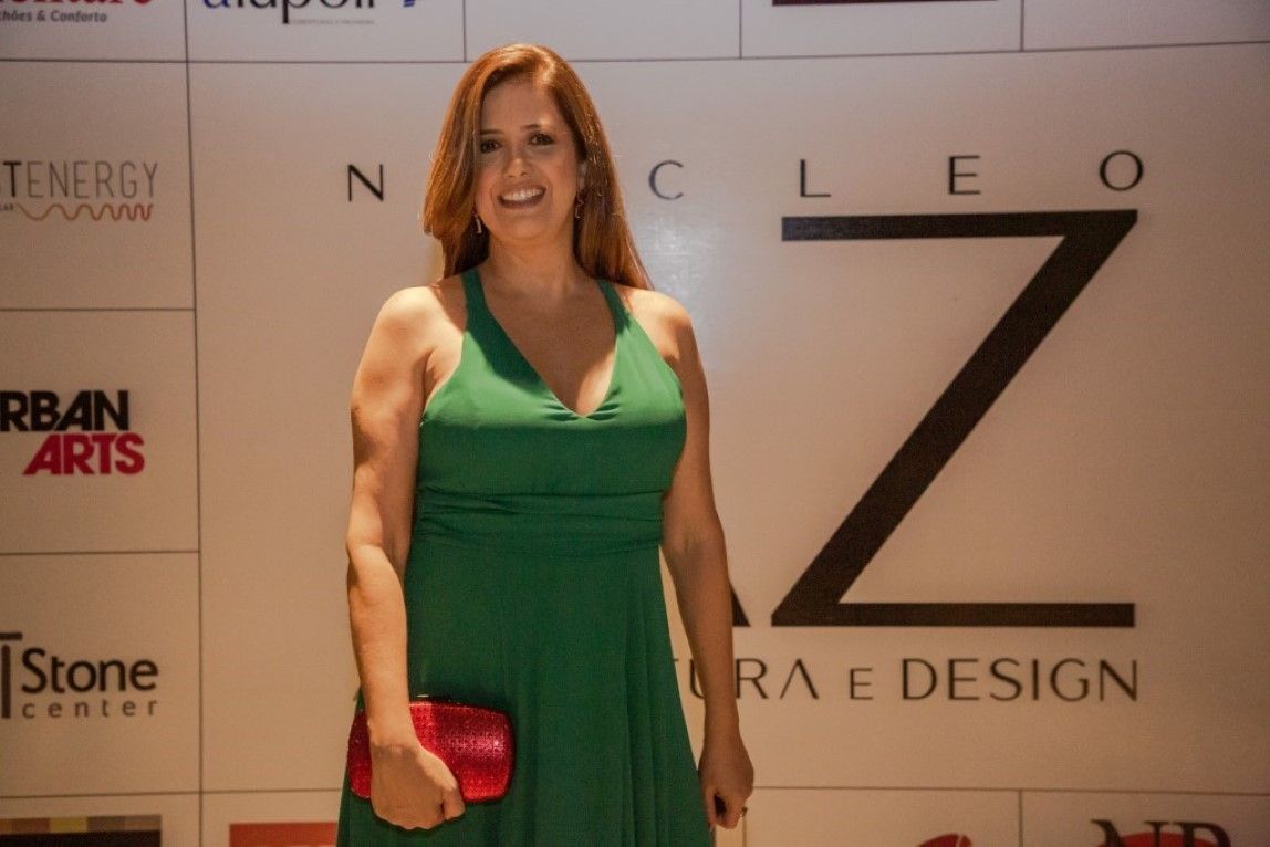 Uma mulher com um vestido verde está parada em frente a uma parede com a letra z nela