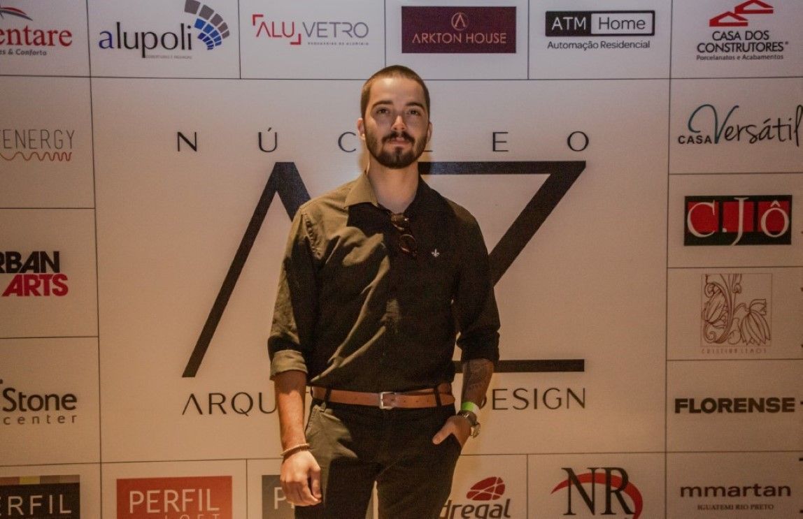 Um homem está em frente a uma parede com logotipos de várias empresas