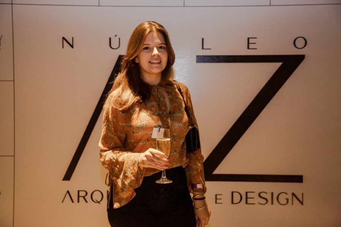 Uma mulher está parada em frente a uma placa que diz nucleo aro e design