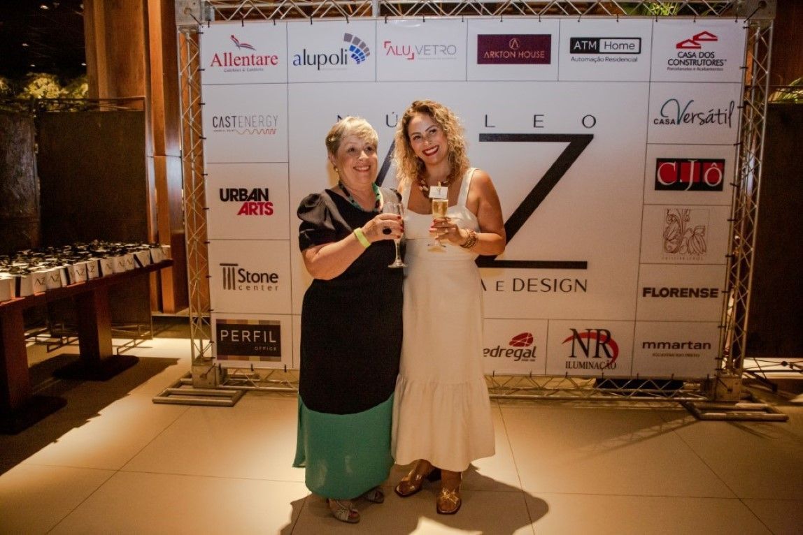 Duas mulheres em pé em frente a uma parede com logotipos