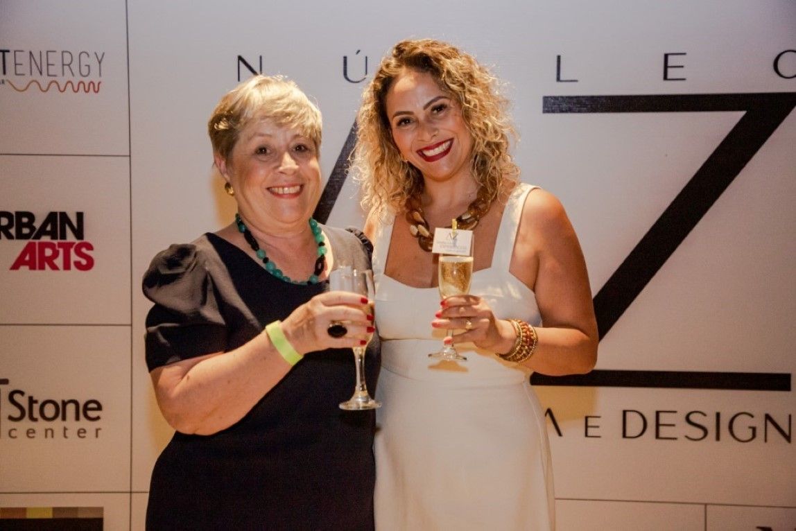 Duas mulheres de pé uma ao lado da outra segurando taças de champanhe