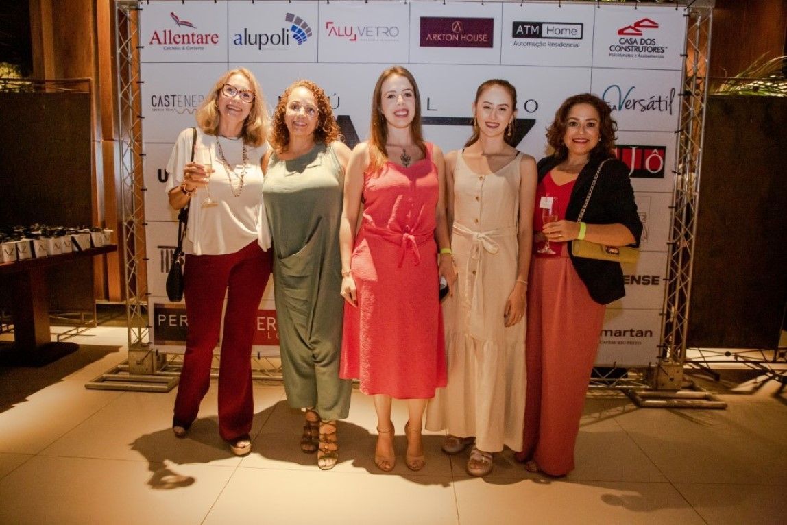 Um grupo de mulheres está posando para uma foto em frente a uma parede com logotipos.