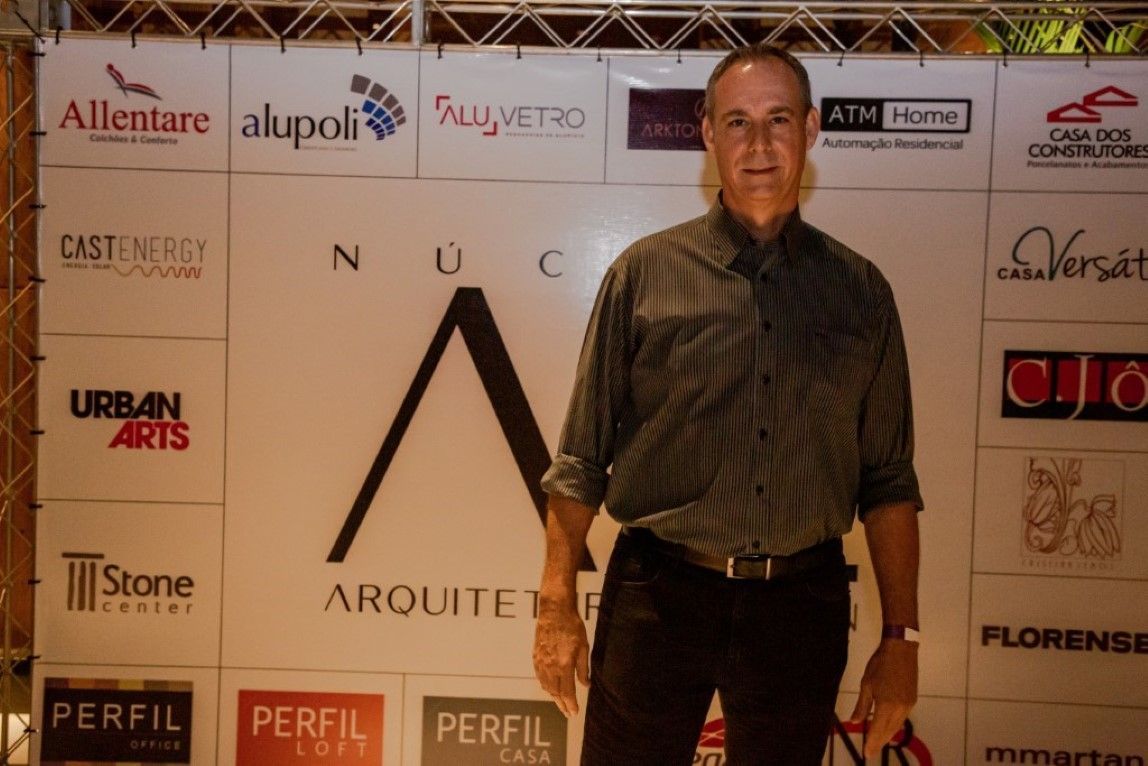 Um homem parado em frente a uma parede com logotipos nela