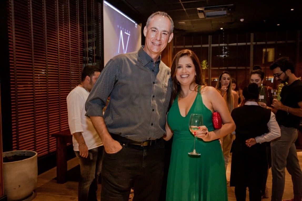 Um homem e uma mulher estão posando para uma foto em uma festa. a mulher está usando um vestido verde.