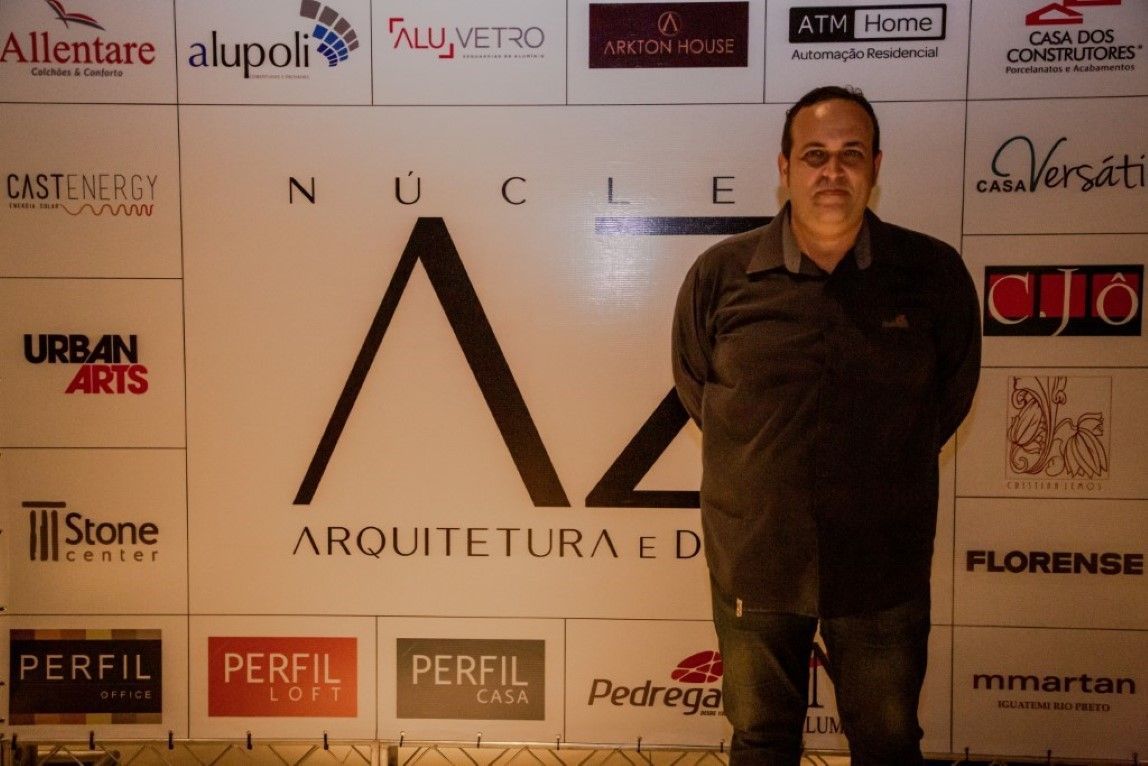 Um homem está em frente a uma parede de logotipos, incluindo um para perfil