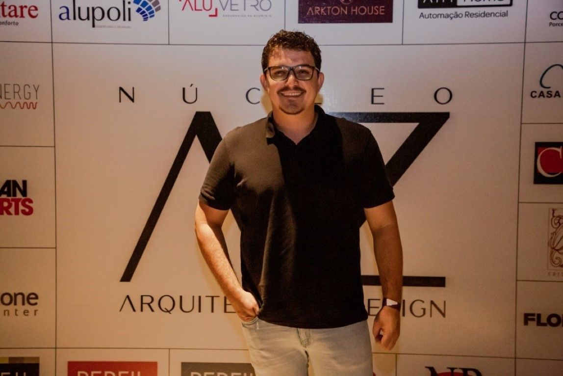 Um homem está parado em frente a uma parede com logotipos nela