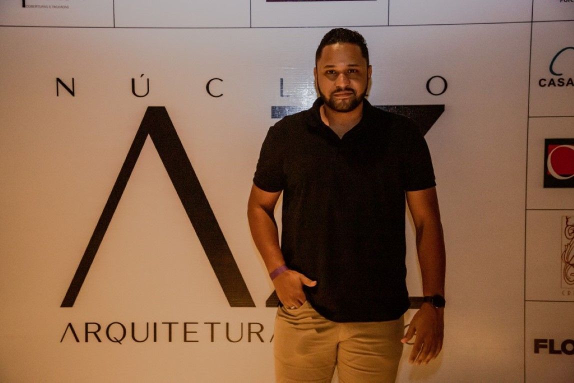 Um homem de camisa preta está em frente a uma parede que diz arquiteto