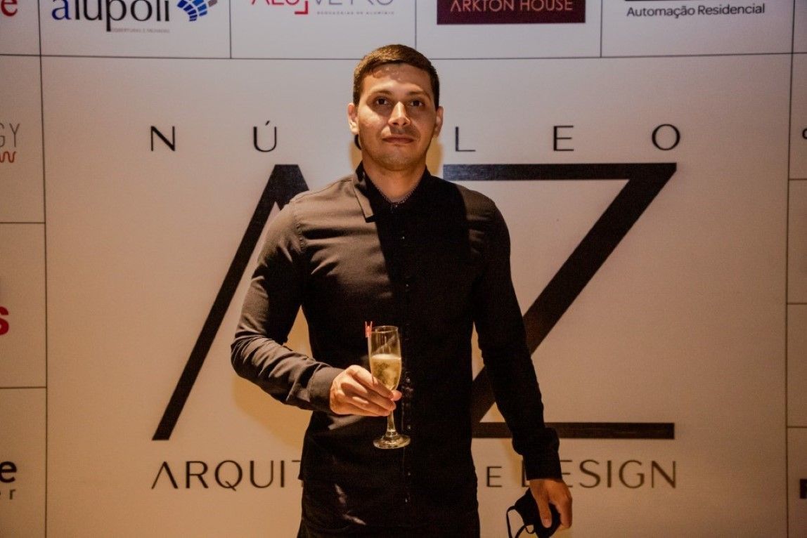 Um homem de camisa preta segura uma taça de champanhe
