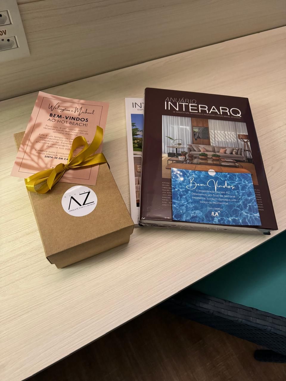 Um livro chamado interaro está sobre uma mesa ao lado de uma caixa de presente