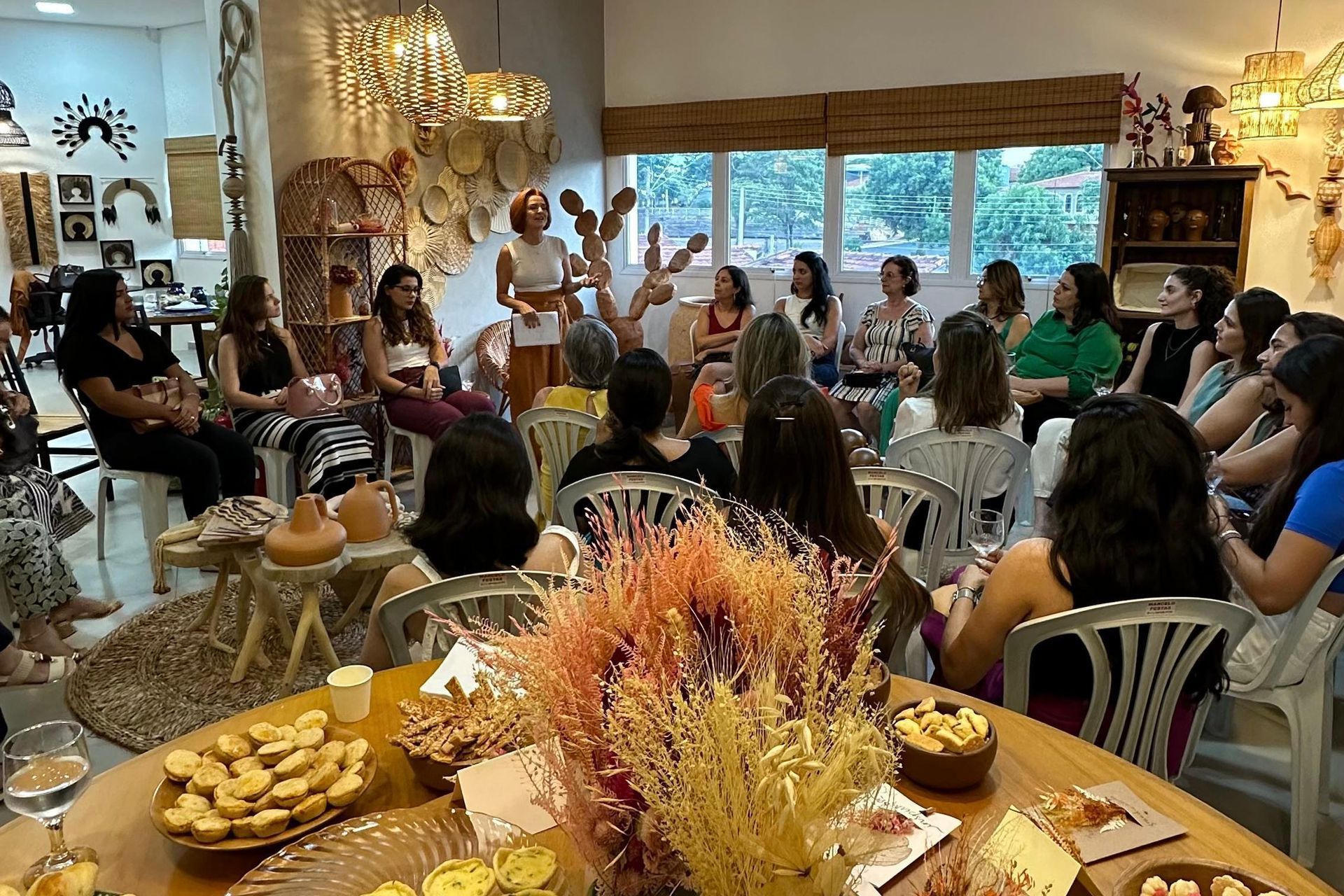 Um grupo de mulheres está sentado ao redor de uma mesa em uma sala.