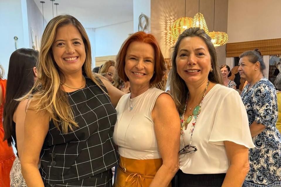Três mulheres estão posando para uma foto juntas em uma sala.
