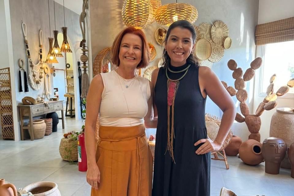 Duas mulheres estão de pé, uma ao lado da outra, em uma sala.
