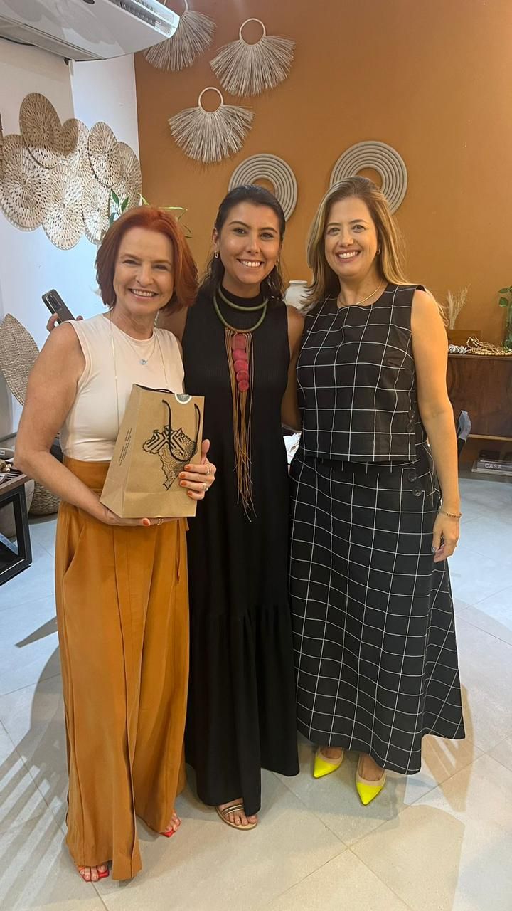 Três mulheres estão posando para uma foto em uma sala.