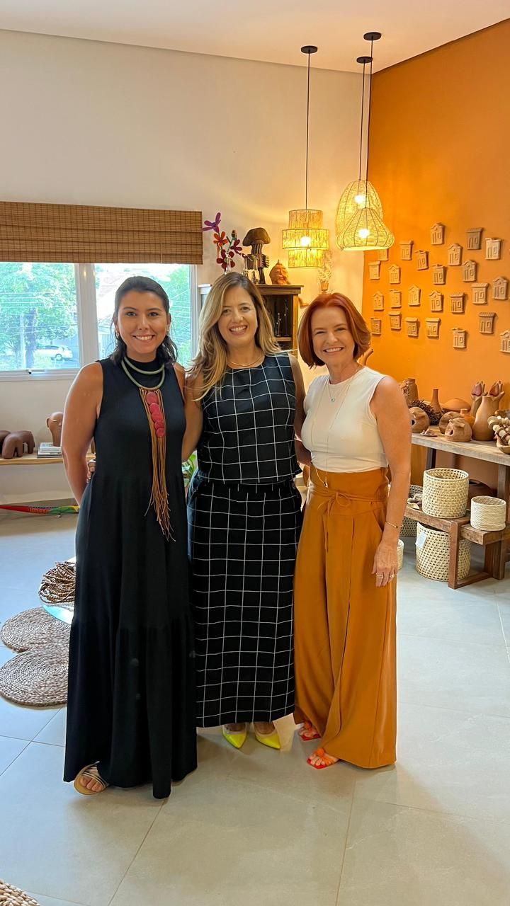 Três mulheres estão posando para uma foto em uma sala.
