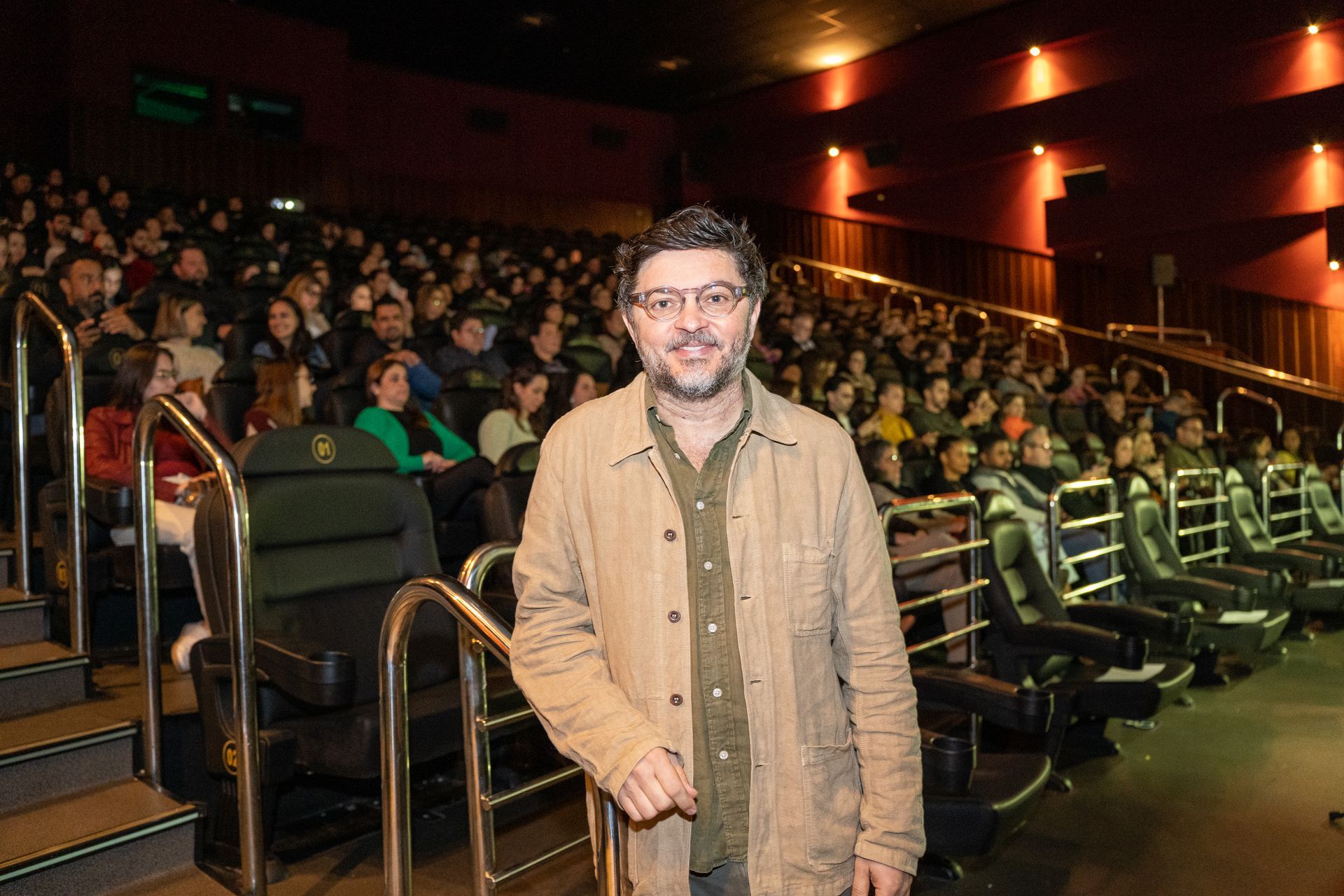 Um homem está parado na frente de uma multidão em um teatro.
