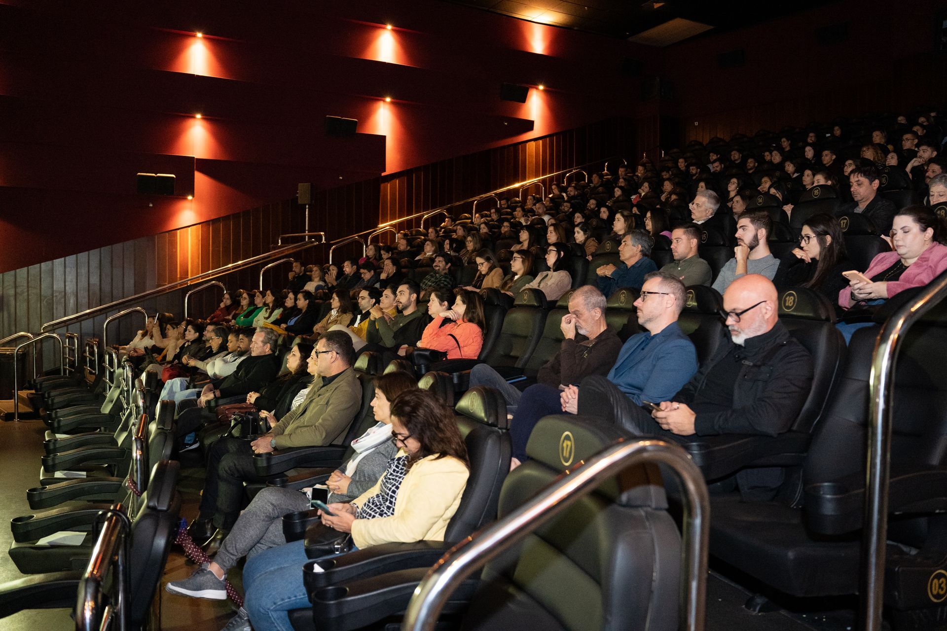 Um grande grupo de pessoas está sentado em um cinema assistindo a um filme.
