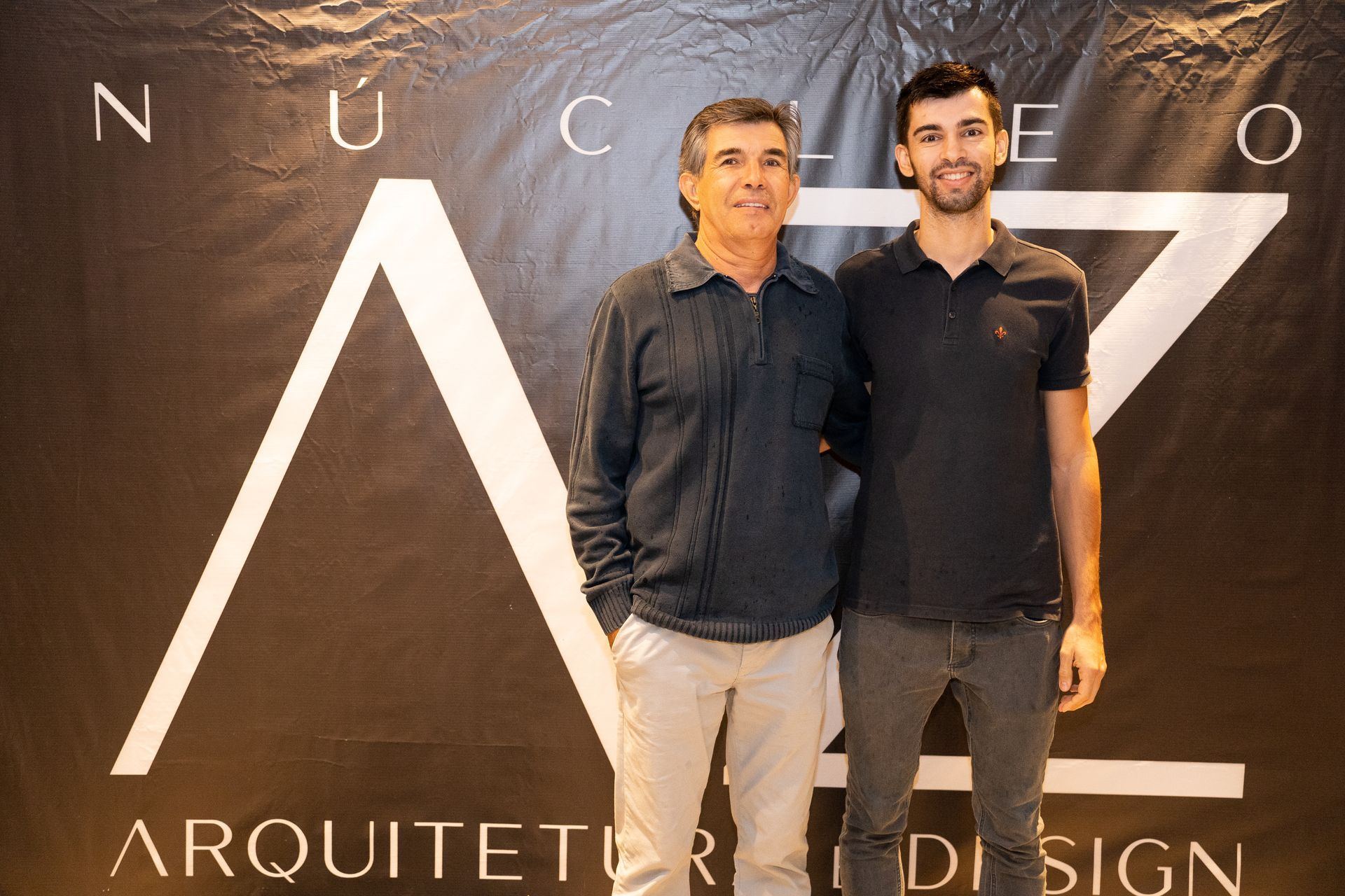 Dois homens parados um ao lado do outro em frente a uma placa que diz arquiteto design
