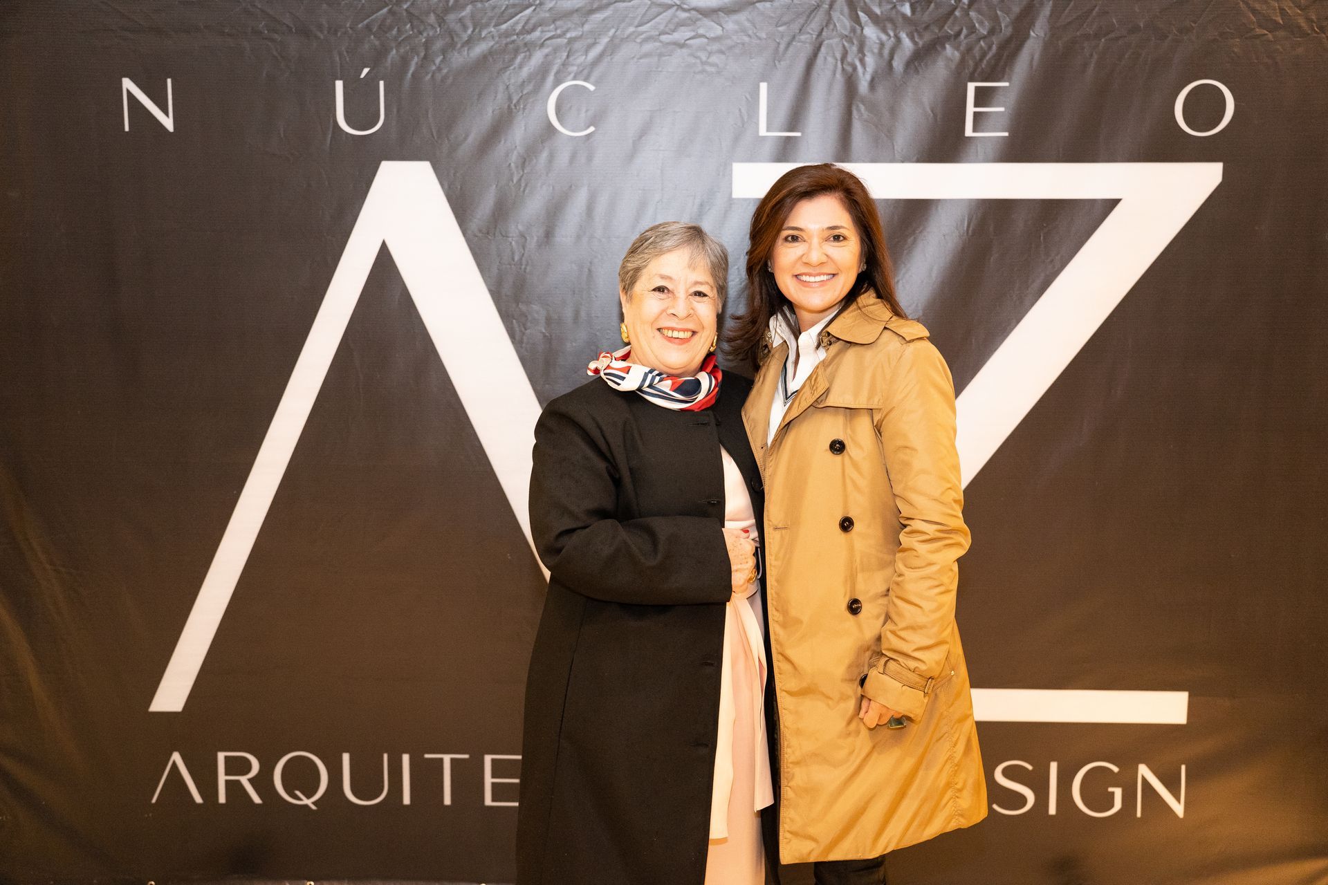 Duas mulheres em pé na frente de uma placa que diz nucleo arquite