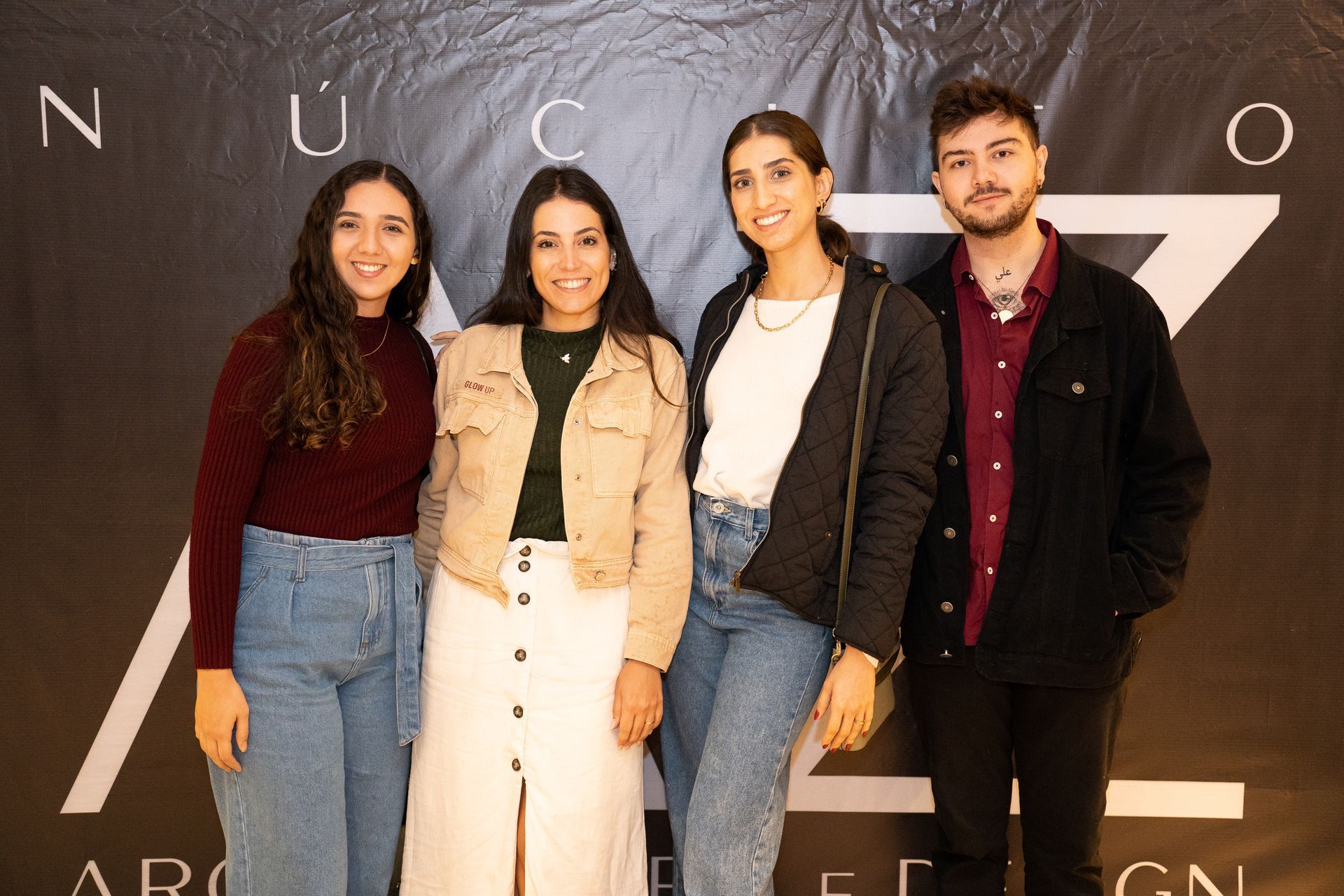 Um grupo de pessoas está posando para uma foto em frente a uma placa.