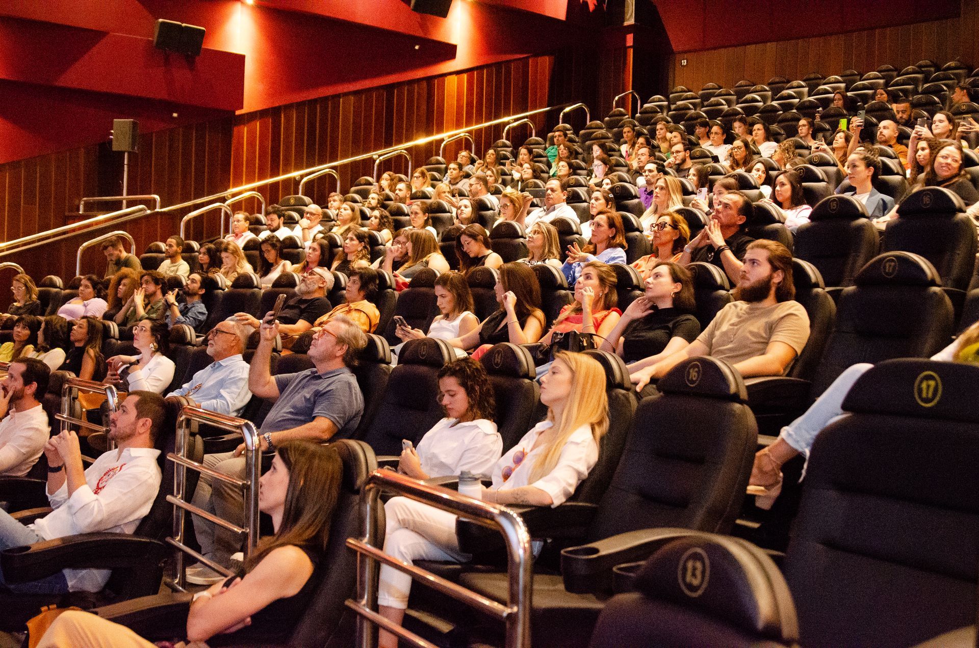 Um grande grupo de pessoas está sentado em um teatro assistindo a um filme