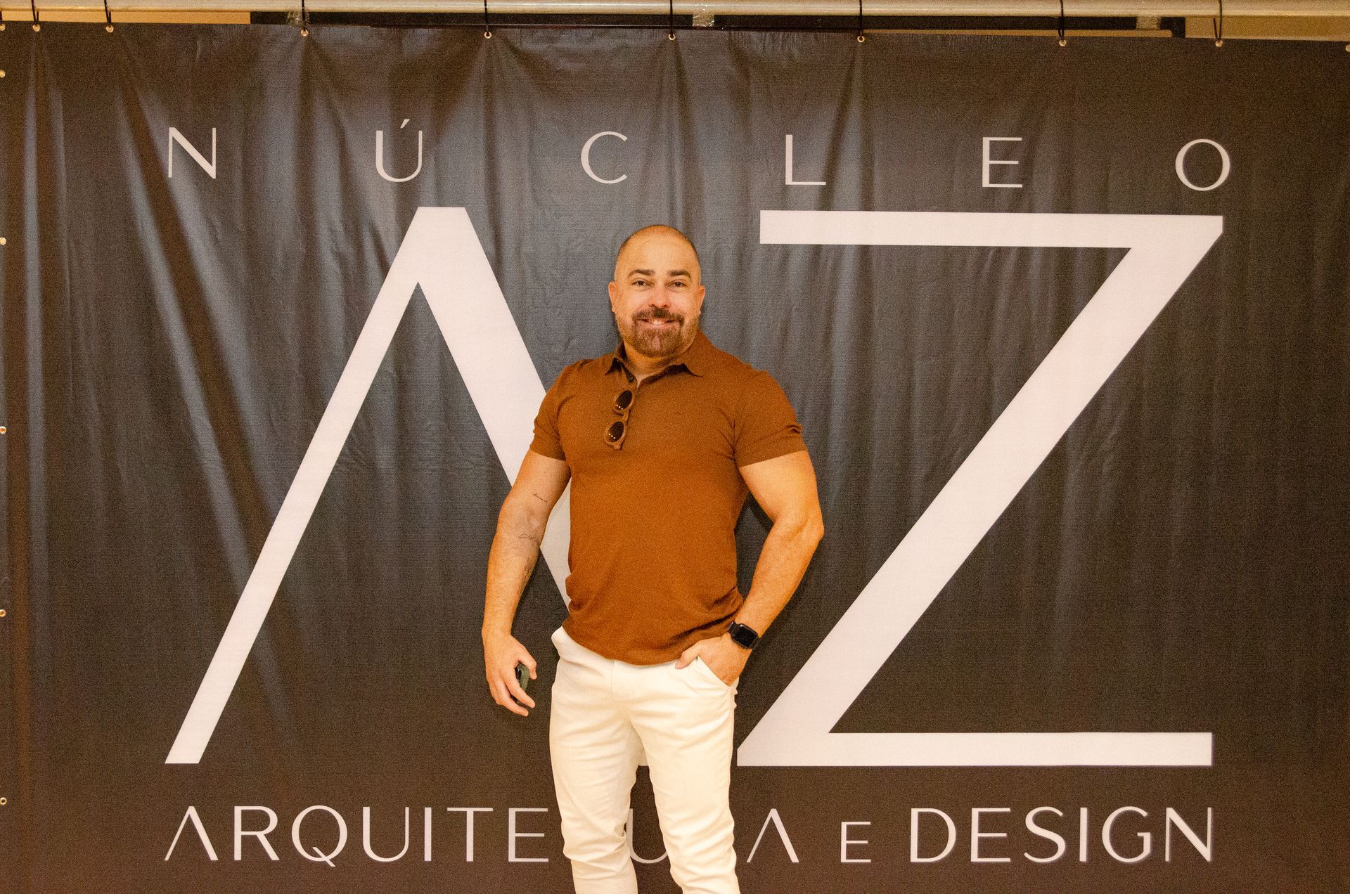 Um homem parado em frente a uma placa que diz nucleo arquiteta e design