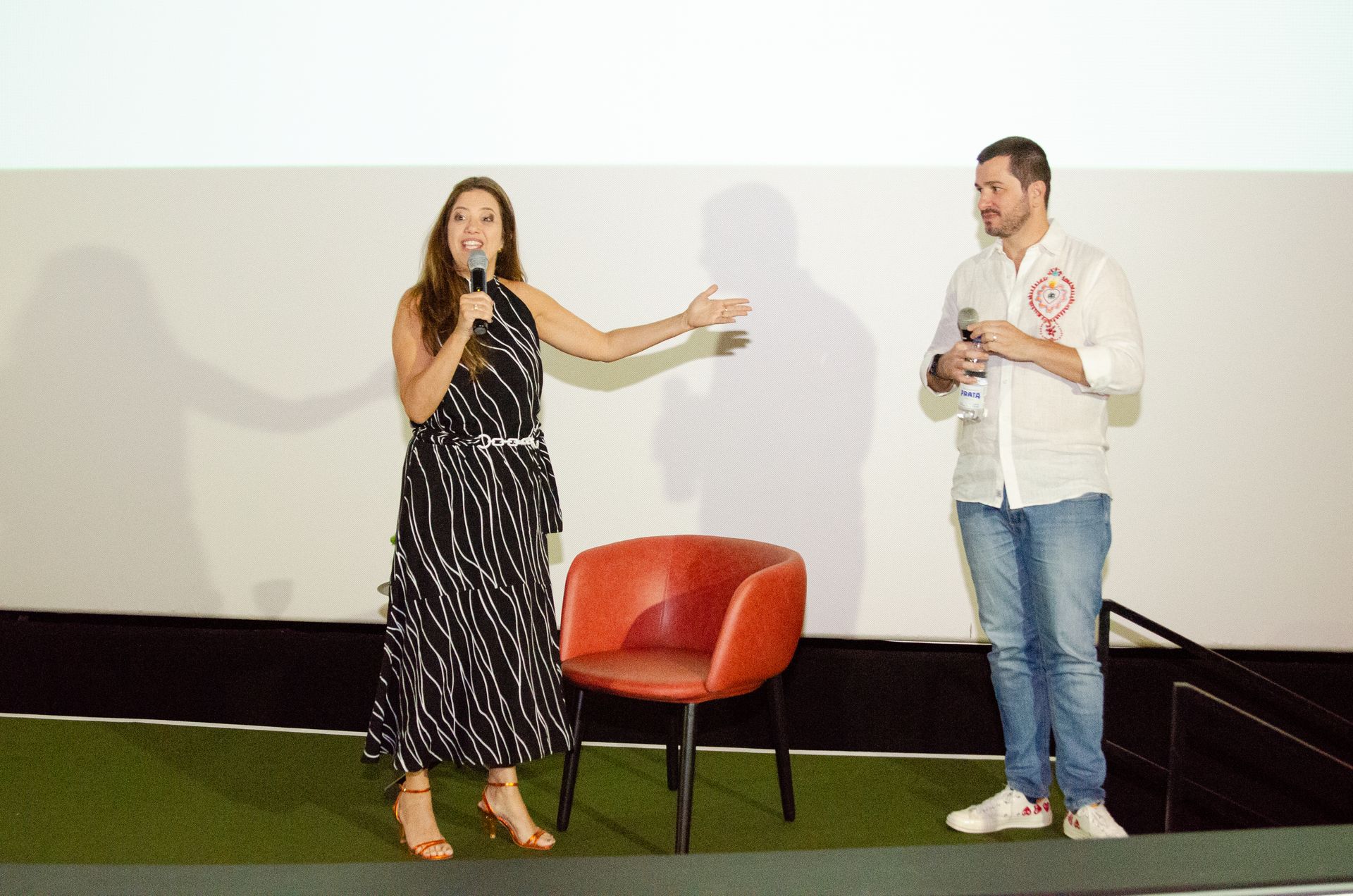 Um homem e uma mulher estão de pé, um ao lado do outro, em um palco.
