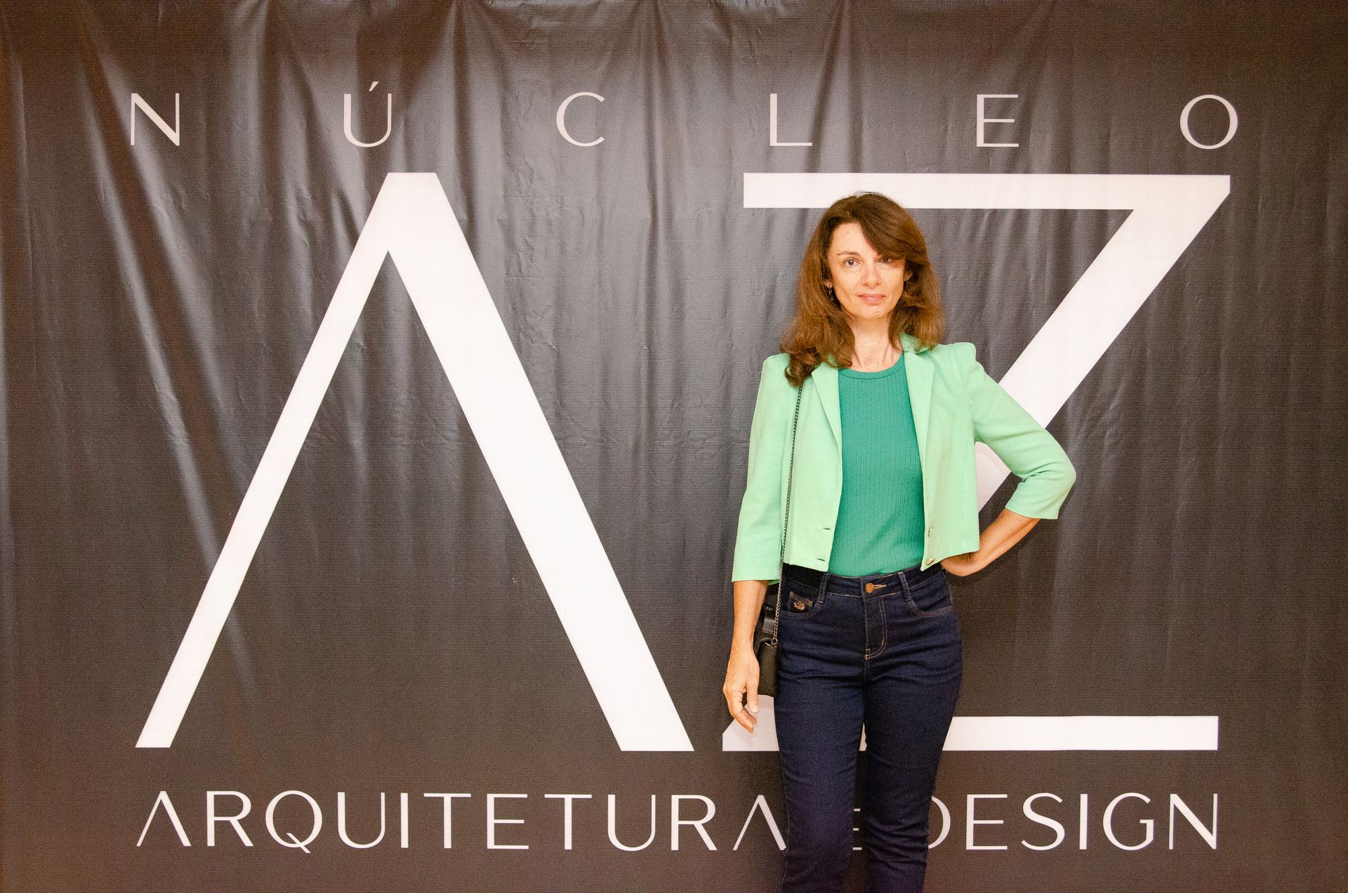 Uma mulher com uma jaqueta verde está em frente a uma placa que diz arquitetura design