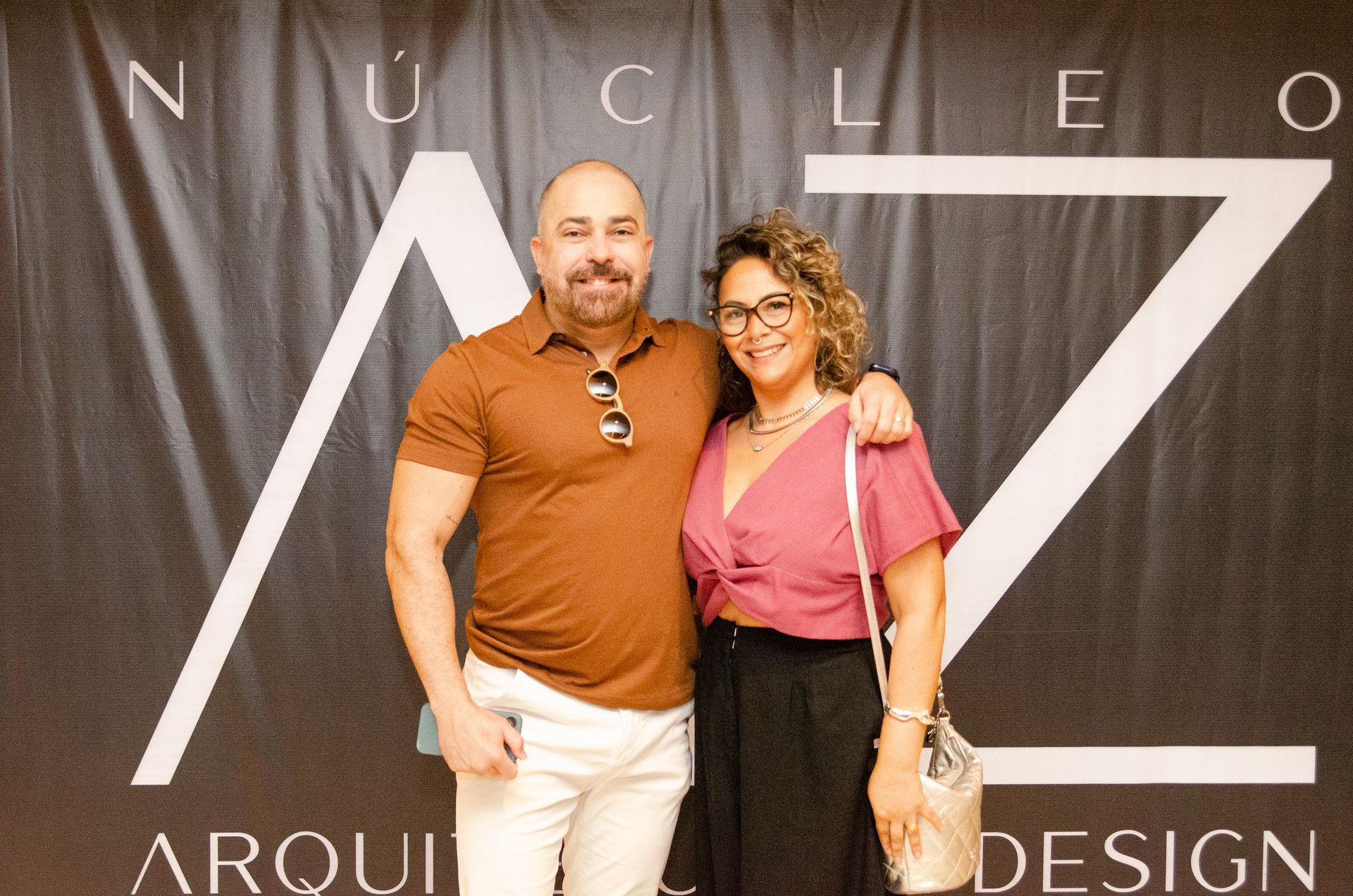 Um homem e uma mulher estão posando para uma foto em frente a uma placa.