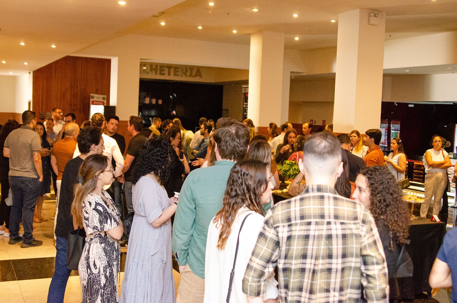 Um grande grupo de pessoas está em pé em uma sala.
