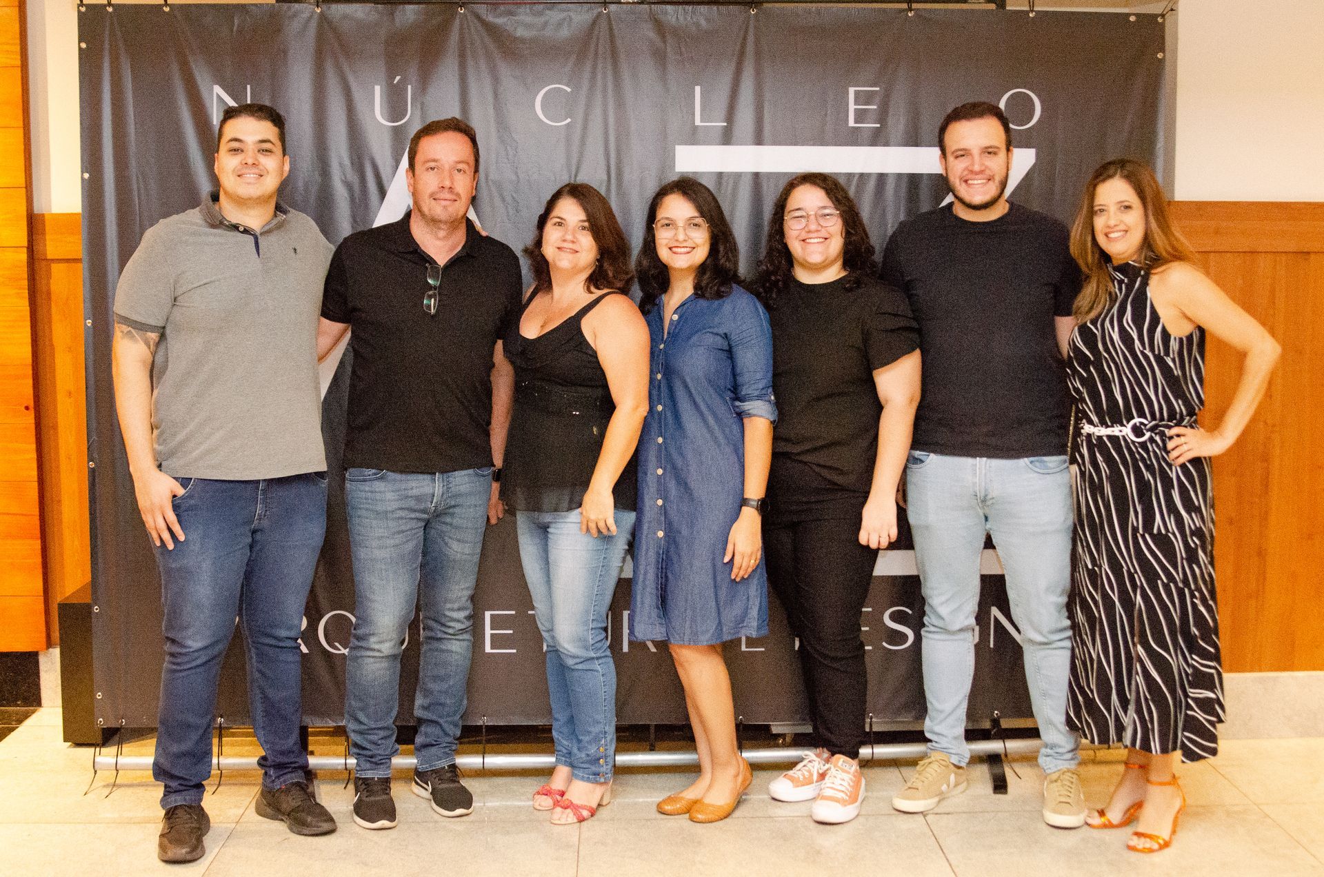 Um grupo de pessoas está posando para uma foto em frente a uma faixa preta.