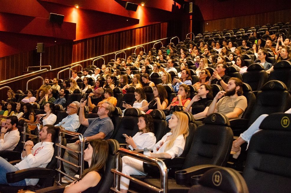 Um grande grupo de pessoas está sentado em um cinema assistindo a um filme.