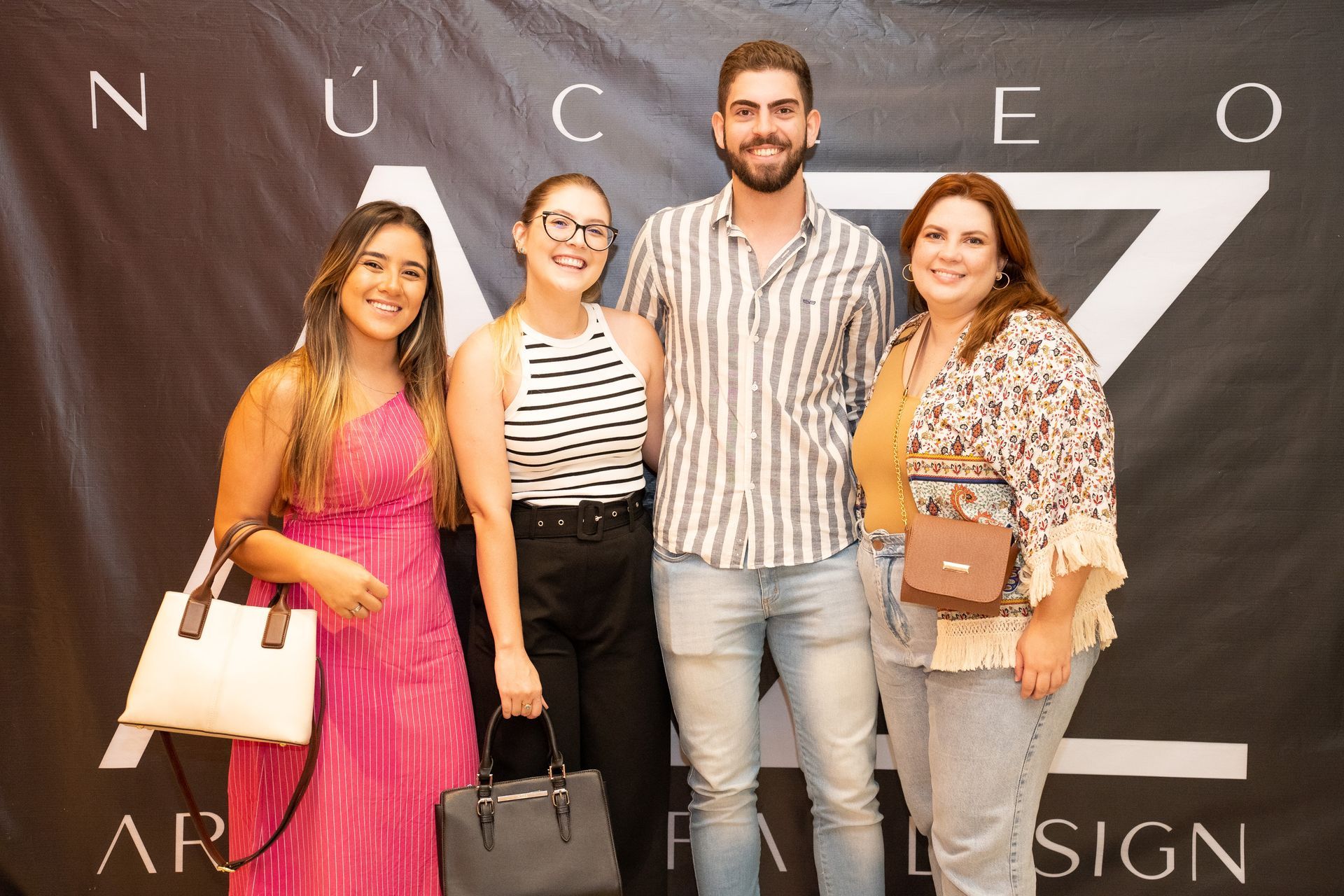 Um grupo de pessoas está posando para uma foto em frente a uma placa.