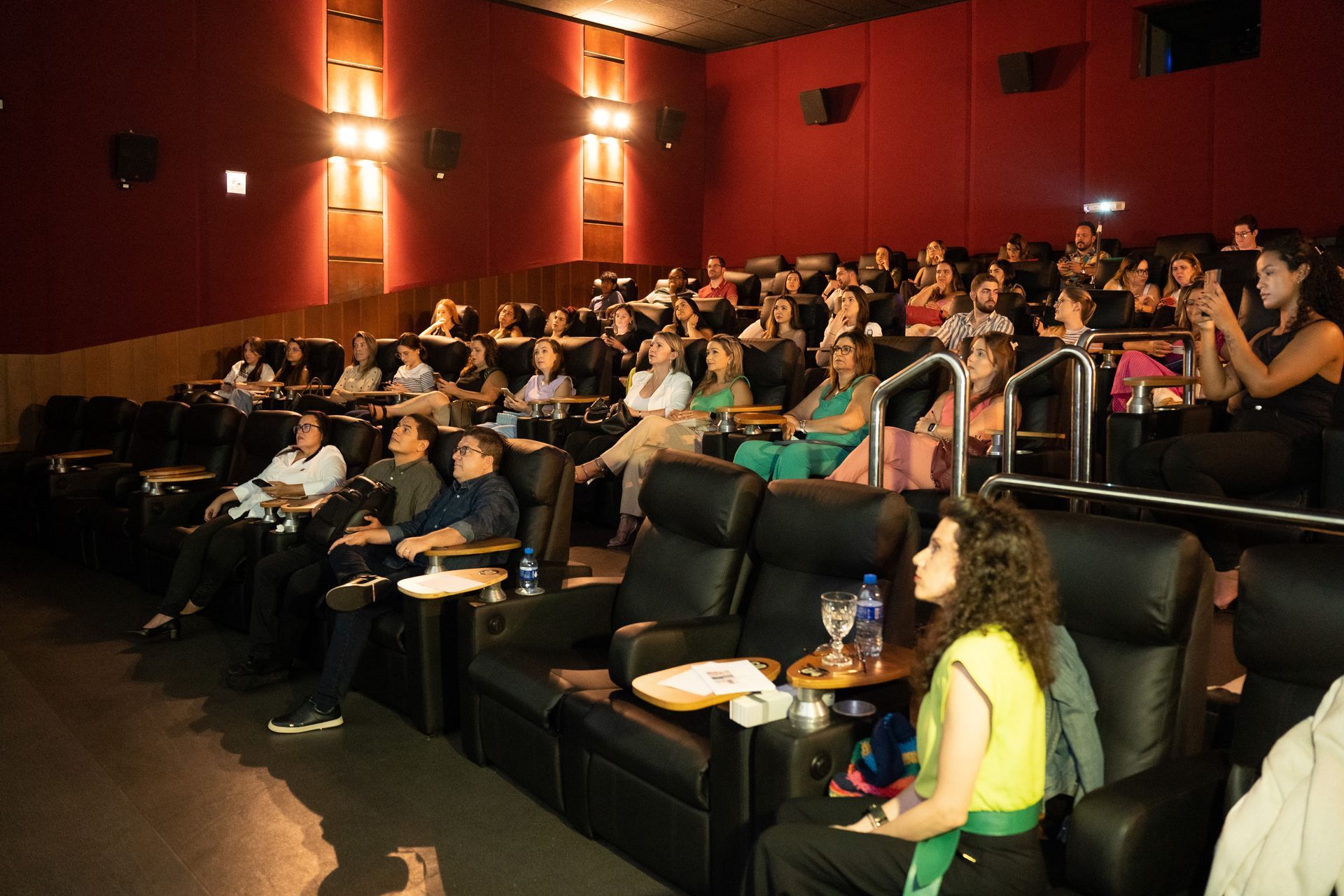 Um grande grupo de pessoas está sentado em um cinema assistindo a um filme.