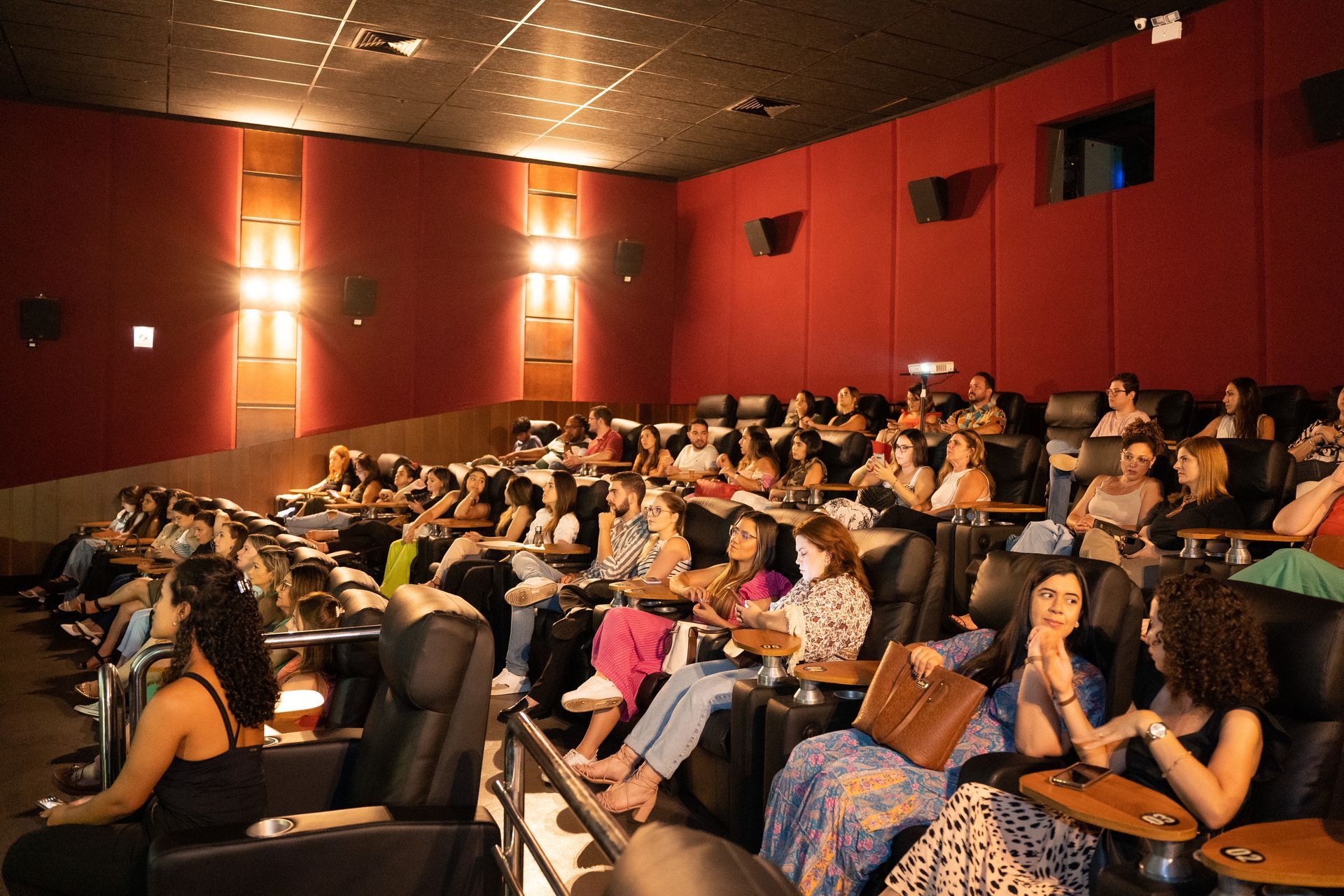 Um grande grupo de pessoas está sentado em um cinema assistindo a um filme.