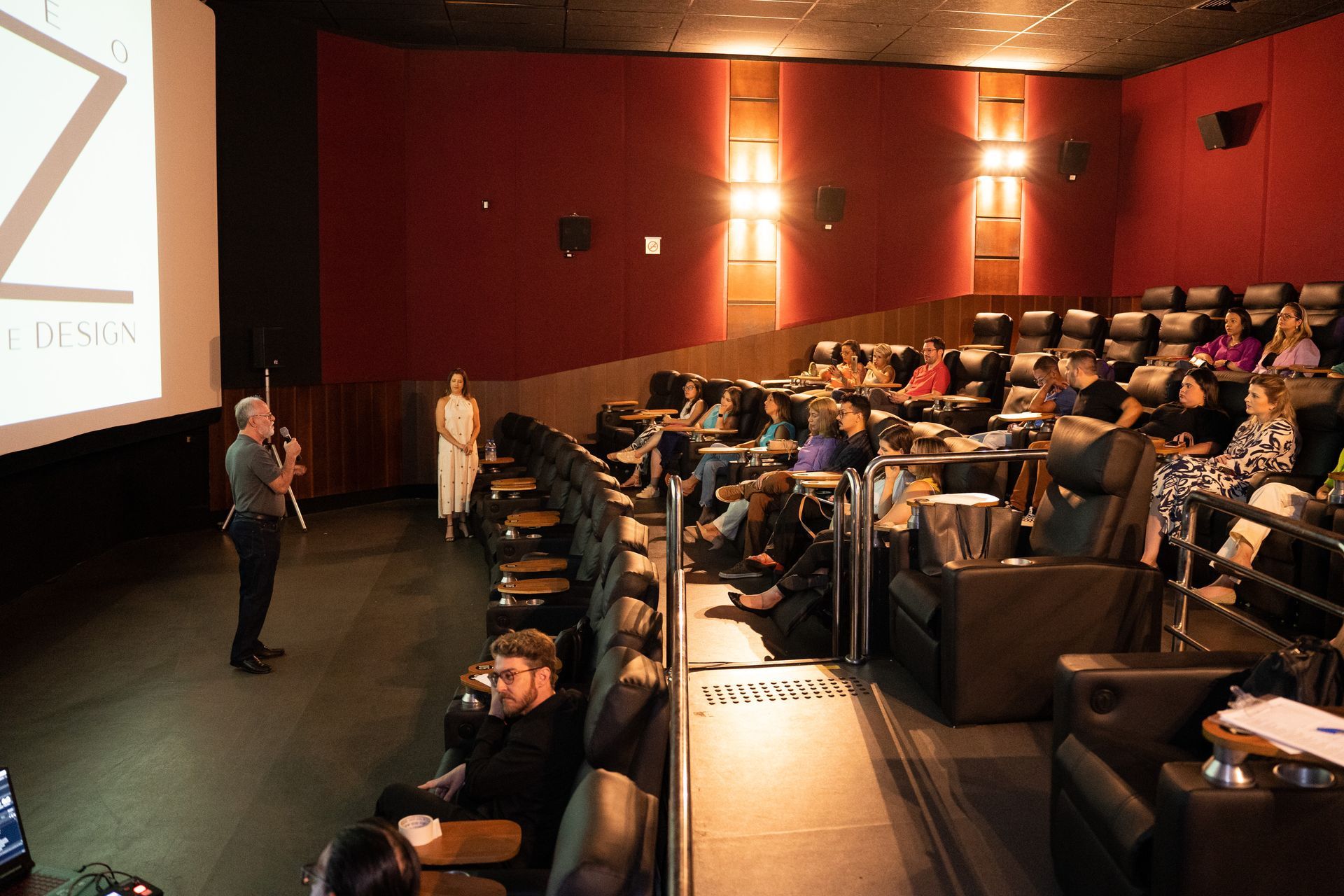 Um homem está fazendo uma apresentação para um grande público em um teatro.
