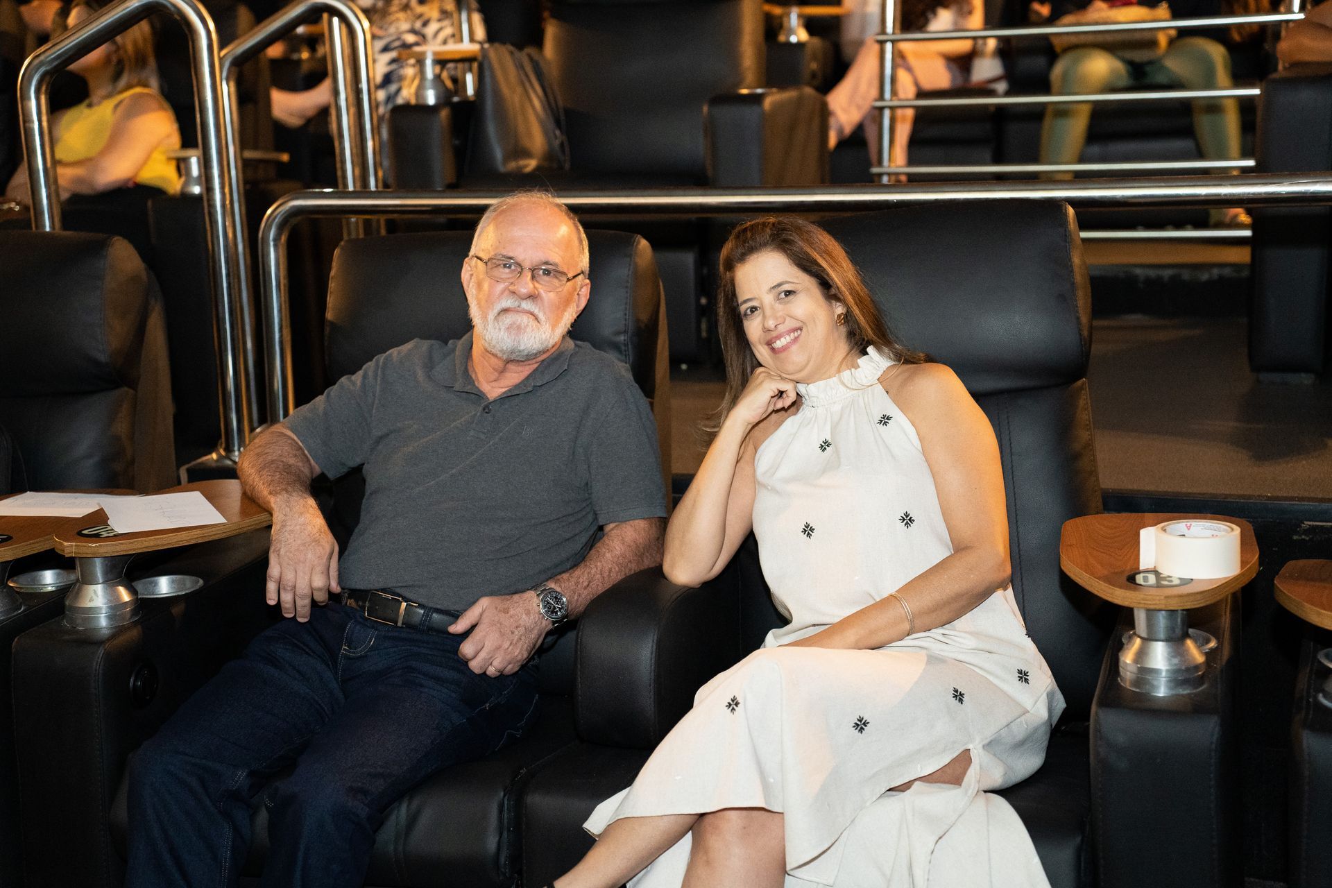 Um homem e uma mulher estão sentados em um sofá em um cinema.