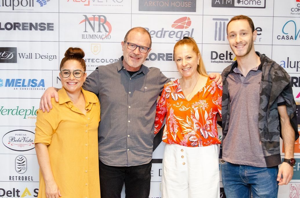 Um grupo de pessoas está posando para uma foto em frente a uma parede com logotipos.