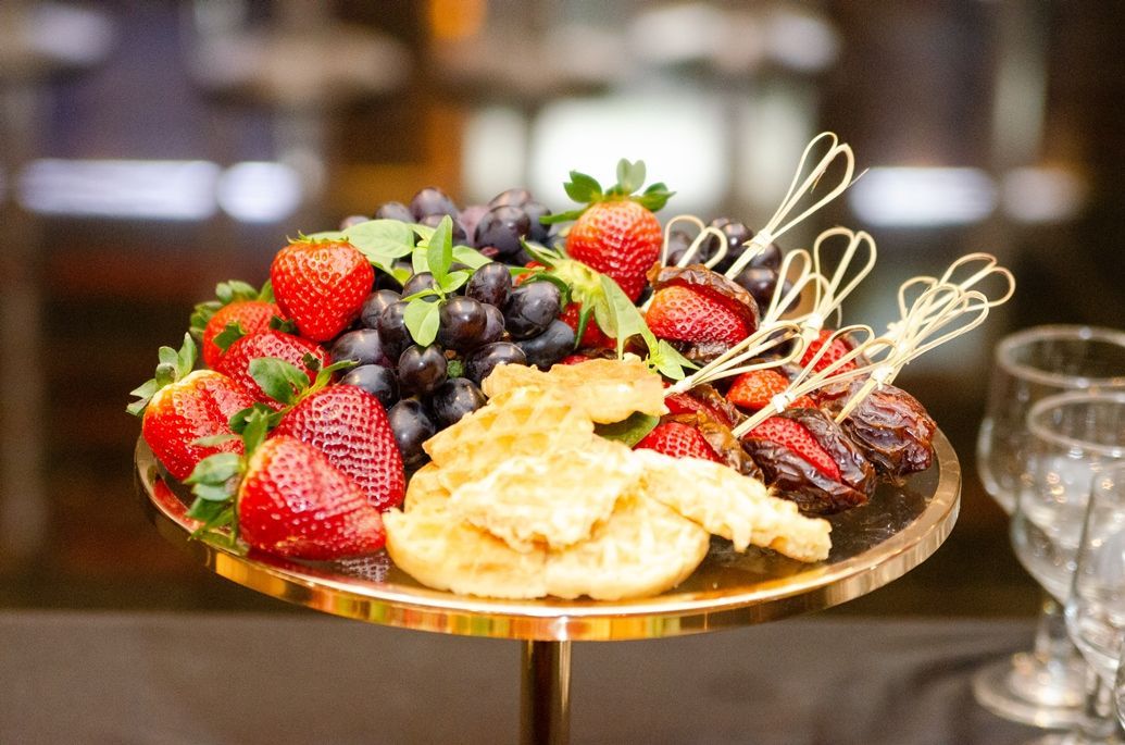 Um prato de frutas e queijo sobre uma mesa com taças de vinho.