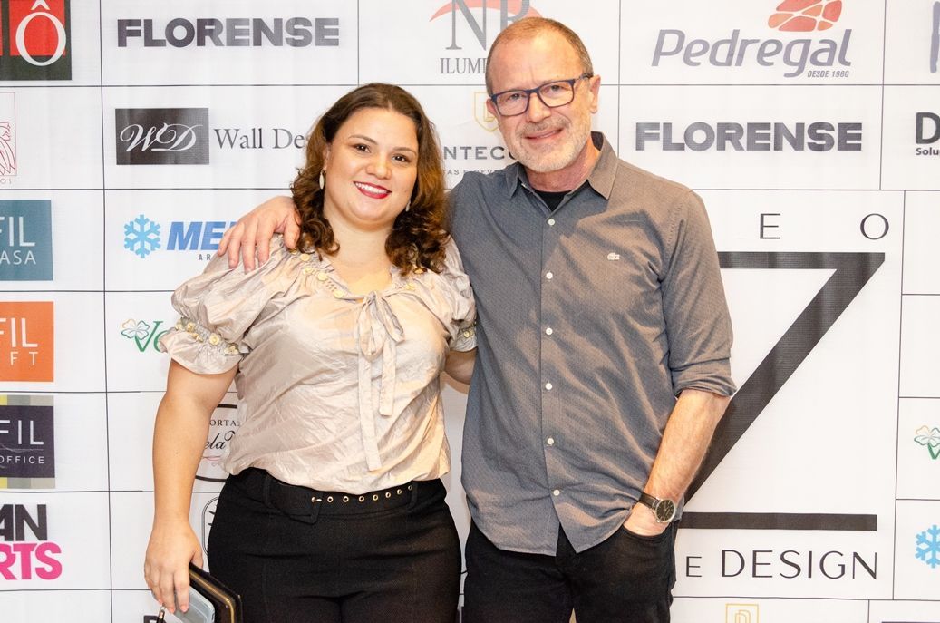 Um homem e uma mulher posam para uma foto em frente a um muro com os logotipos do florense e do pedregat